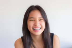 A young lady is smiling brightly, showcasing her dental braces