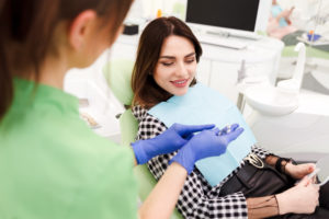 A woman is smiling while selecting the type of dental crown shown by the dentist.