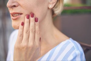 A lady is holding her cheek because of a toothache