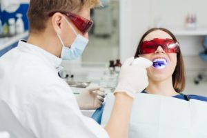 The dentist is performing a teeth whitening procedure on his patient