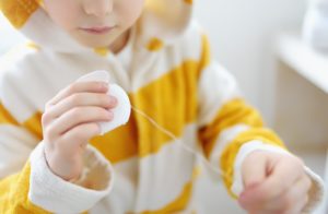 A child is holding dental floss