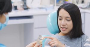 A female patient is pointing to a dental model.