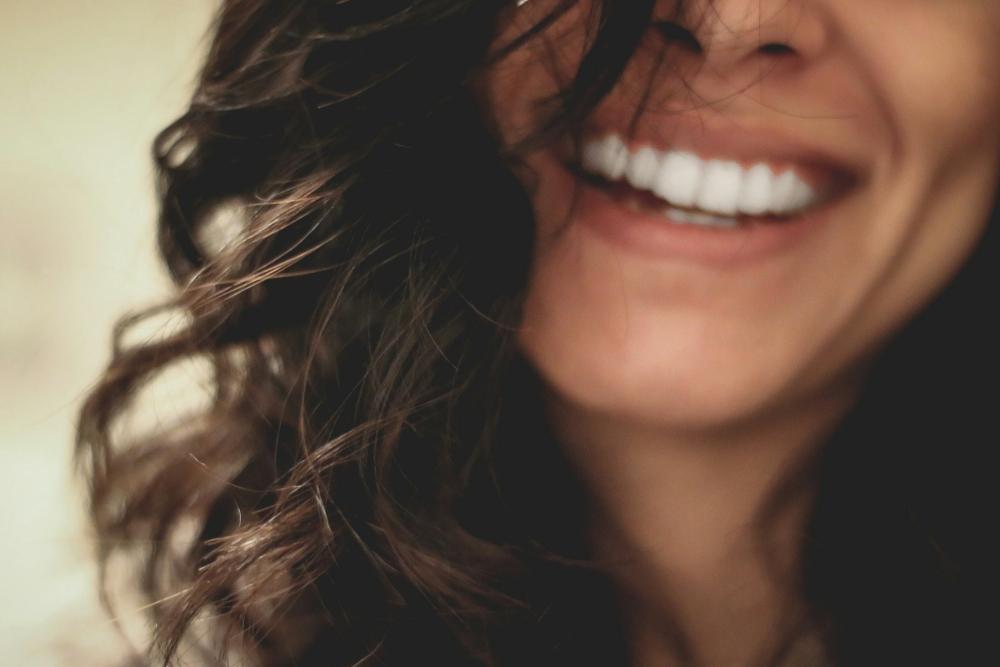 A curly-haired lady is smiling brightly, demonstrating excellent dental health