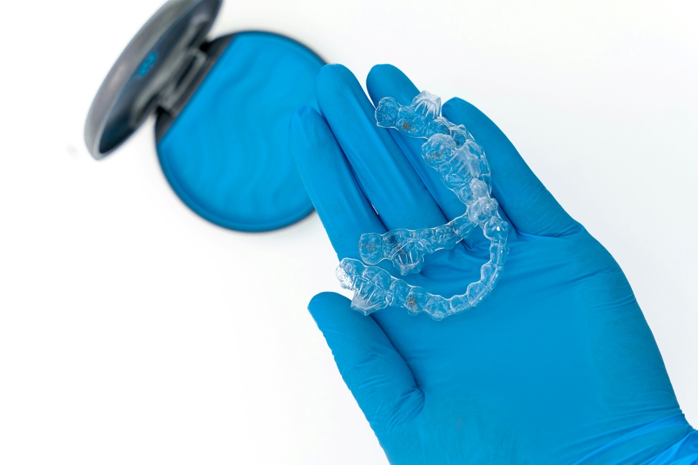 clear aligners held on the palm of a dentist wearing gloves