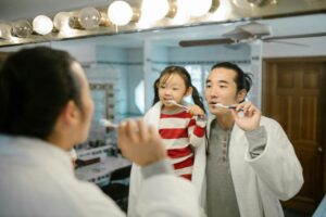 a man demonstrating teeth brushing to a girl