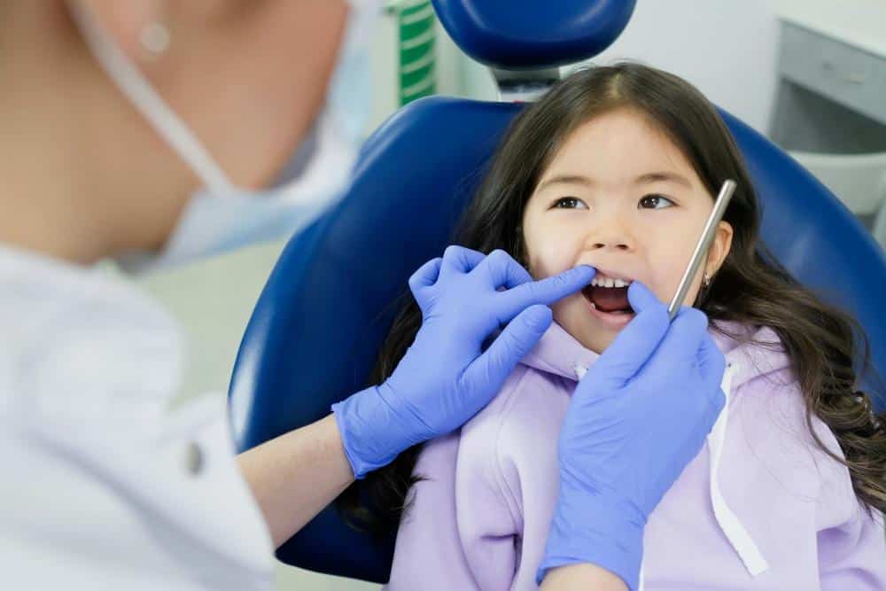 Alt text: an Asian Chinese girl having her teeth examined by a dentist